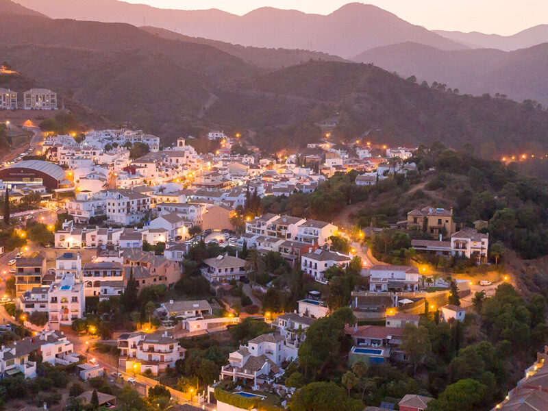 Aerial view of Benehavis with city lights and hillside roads.