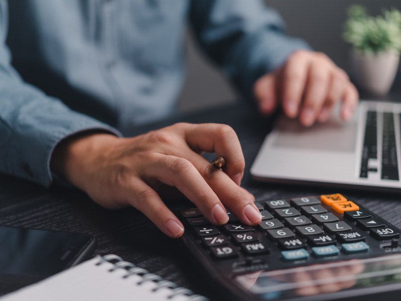 Business proffessional using calclulator and budget and tax documents.
