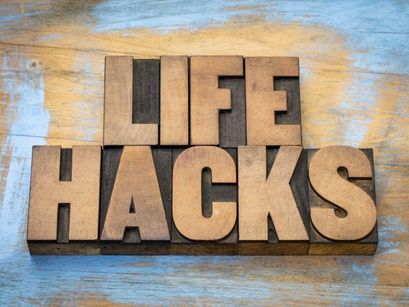 THe word life hacks in front of a wooden painted table.
