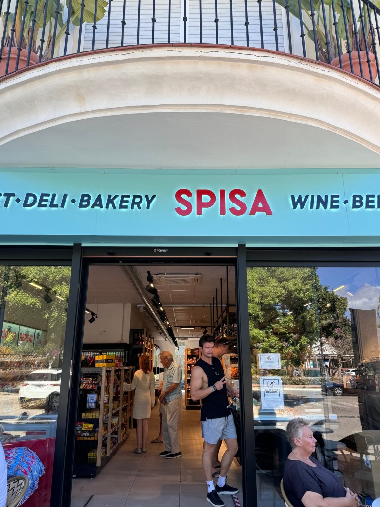 A man outside Spisa Foodmarket entrence showing piece with his hand