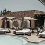 Modern poolclub sorrounded by sunbeds and palms