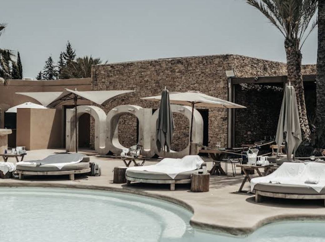 Modern poolclub sorrounded by sunbeds and palms