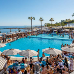 Big pool club sorrounded by sunbeds infront of the ocean